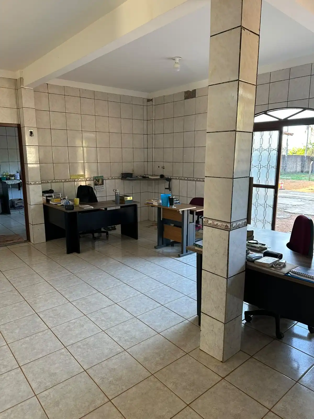 Sala da equipe pastoral com mesas de trabalho, livros e acesso à área externa