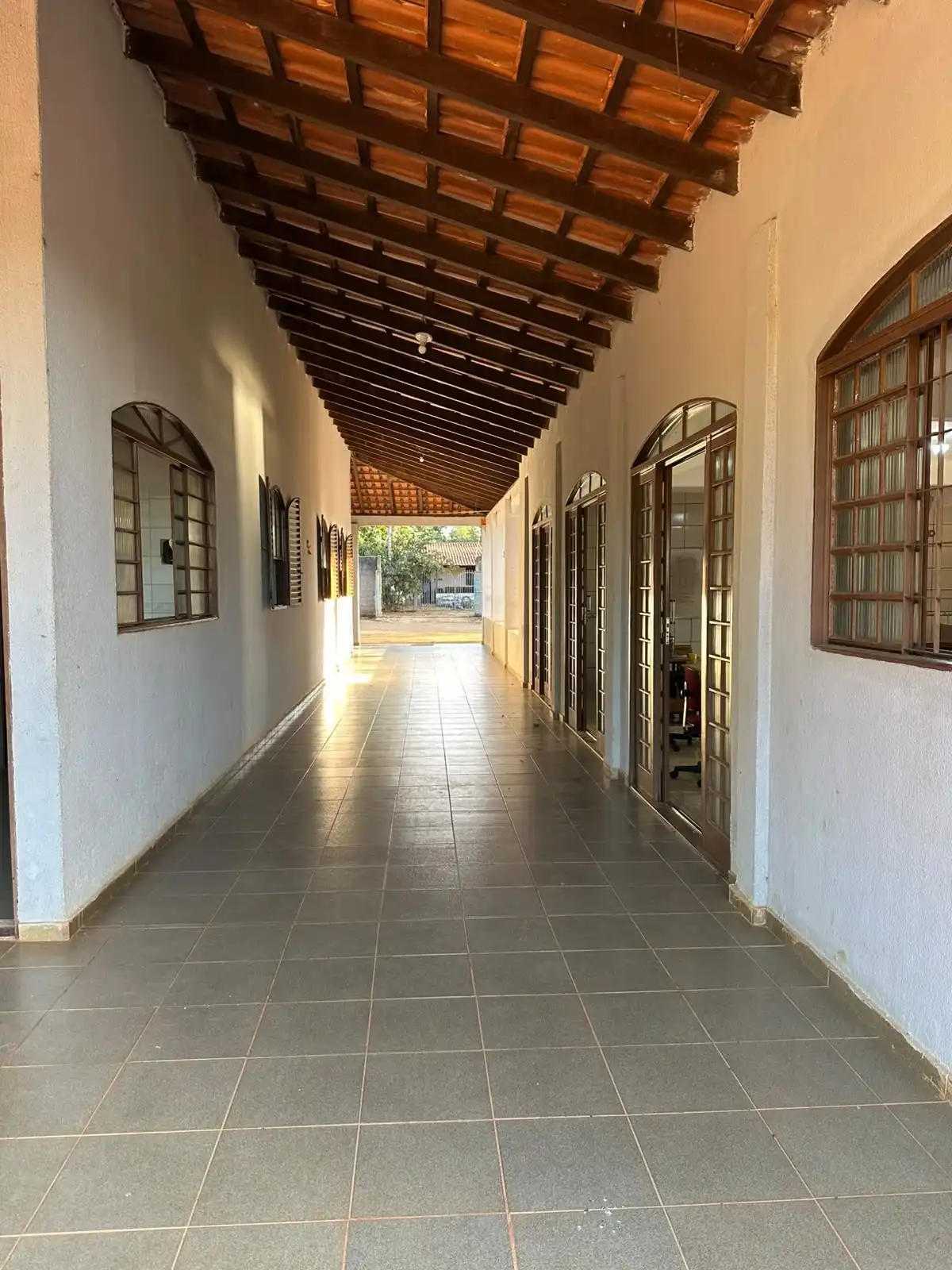 Corredor coberto com telhado de madeira e portas em arco que dão acesso às salas do campus