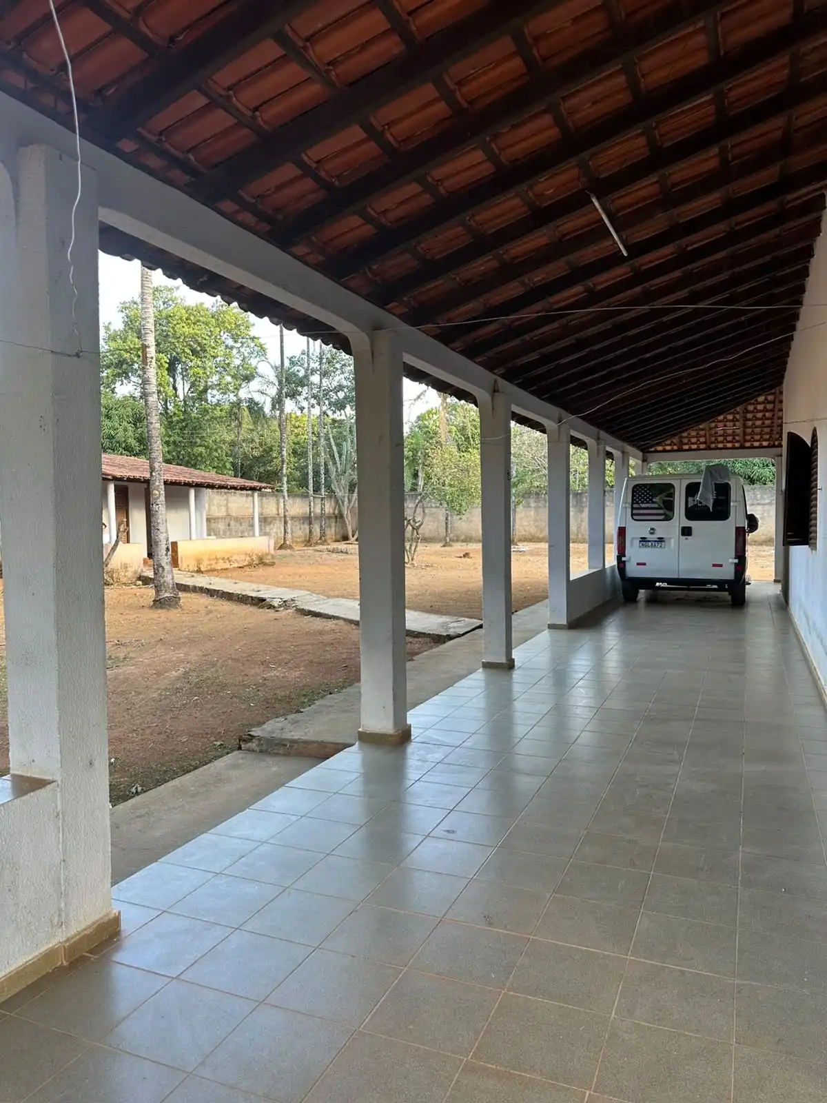 Varanda com pilares brancos voltada para o pátio interno e a van do ministério estacionada